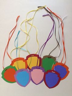 an assortment of colorful tags hanging from strings on a white wall with string attached to them