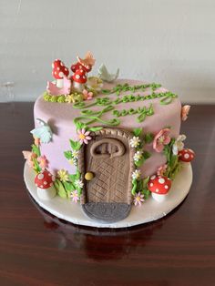 a pink cake with mushrooms and flowers on it is sitting on a table next to a wall