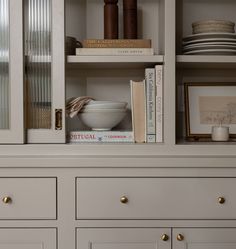 a book shelf with some books and bowls on top of it next to other items