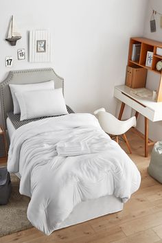 a white bed sitting in a bedroom next to a wooden desk and bookcases