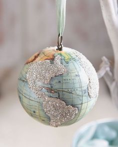 an ornament hanging from a tree with a globe on it's side