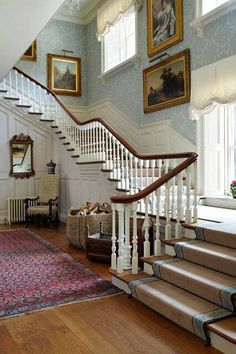 a staircase in a house with blue walls and carpeted flooring, framed pictures on the wall