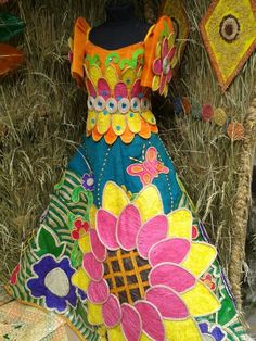 a dress made out of fabric and flowers on display in front of hay bales