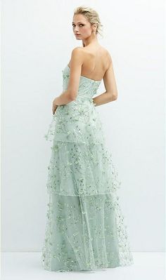 a woman in a strapless dress with flowers on the bouncy skirt is looking back