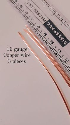 two copper wires sitting next to each other on top of a white table with measuring tape