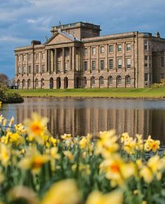 a large building sitting on top of a lush green field next to a body of water