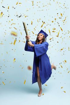 a woman in graduation cap and gown holding a baseball bat while confetti falls around her