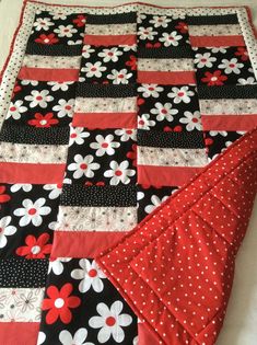 a black and red quilt with white flowers on it