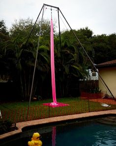 a yellow rubber duck floating on top of a pool next to a tall pink pole