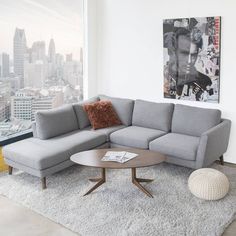 a living room with a couch, coffee table and large window looking out on the city