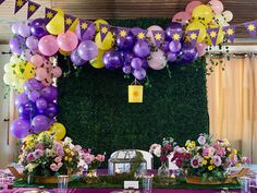 the table is set up with purple, yellow and pink balloons