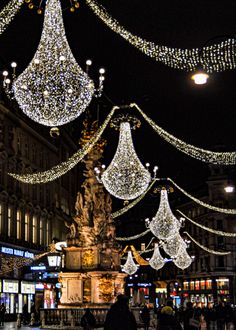 people walking down the street in front of christmas lights and chandeliers hanging from the ceiling