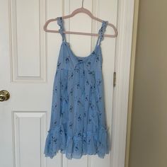 Never Worn, Beautiful Sun Dress. Doubled Lined. Adjustable Straps And Tie In Front Flowy Light Blue Mini Dress With Floral Print, Flowy Blue Floral Mini Dress, Blue Floral V-neck Dress For Daywear, Blue Floral Sundress For Brunch, Blue Flowy Floral Dress With Ruffles, Flowy Blue Floral Dress With Ruffles, Blue Sleeveless Flowy Floral Dress, Blue Summer Floral Dress With Ruffles, Blue Flowy Sleeveless Floral Dress