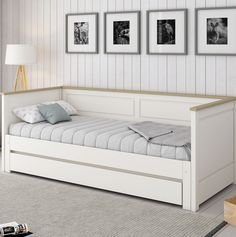 a white day bed with two pictures on the wall