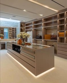 a large open closet with shelves and counter tops in an office space that is well lit by recessed lighting