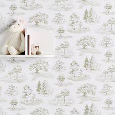 a white teddy bear sitting on top of a book shelf next to a wallpaper