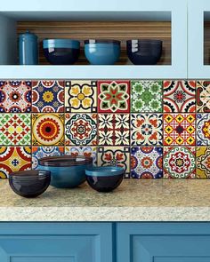 colorful tile backsplash in a kitchen with bowls on the counter and blue cabinets