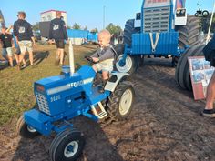 a small child riding on the back of a blue tractor