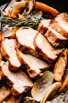 sliced pork and potatoes in a skillet with rosemary garnish on top, ready to be eaten