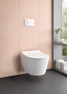 a white toilet sitting next to a window in a room with wooden walls and flooring