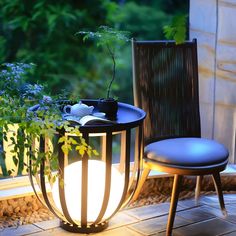 two chairs and a table on a patio with plants in the background at night time