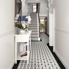 the hallway is decorated in white and black with flowers on the table next to it