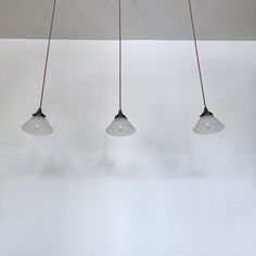 three light fixtures hanging from a ceiling in a room with white walls and flooring