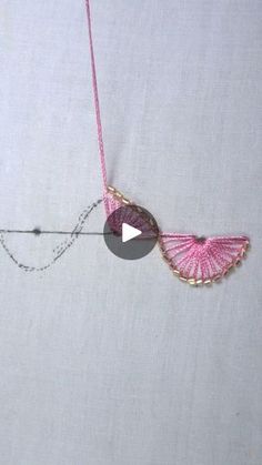 a pink necklace with an owl charm hanging from it's side on a white surface