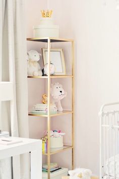 a baby's room with pink walls and gold shelving unit in the corner