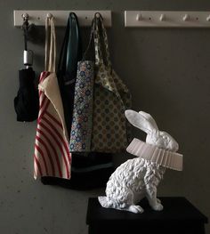 a white rabbit figurine sitting on top of a shelf next to a tie rack