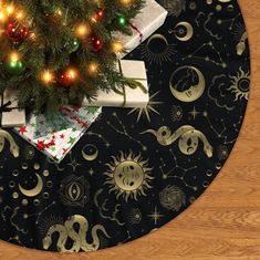 a christmas tree with presents under it on a black table cloth covered in gold stars and moon designs