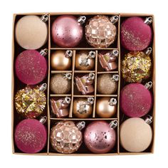 a box filled with assorted christmas ornaments on top of a white background, including pink and gold baubles