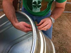 a man wearing a st patrick's shamrock t - shirt holding onto a metal barrel