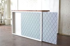 a white and blue cabinet sitting on top of a floor next to a brick wall