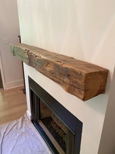 a fireplace mantel made out of wood with a white painted wall in the background