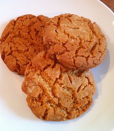 three cookies on a white plate sitting on a table