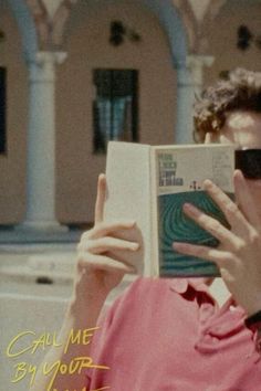 a man in sunglasses reading a book while holding his hand up to his face with the caption call me by your name