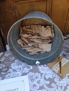 a large metal bowl filled with lots of wooden spoons on top of a table