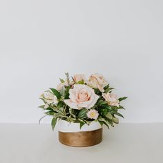 a white vase filled with pink flowers on top of a table