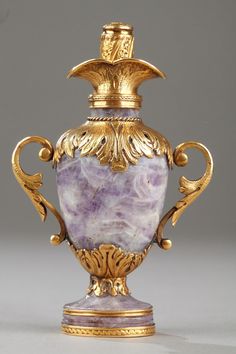 an ornately decorated urn with gold trimmings and purple marble in the center