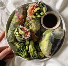 a white plate topped with lots of veggies next to a cup of sauce