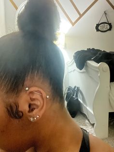 a close up of a person with ear piercings on their ears and hair in a bun