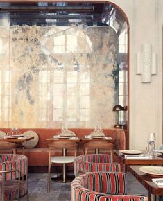 the interior of a restaurant with striped chairs and tables in front of a large window