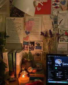 a laptop computer sitting on top of a wooden desk next to a vase filled with flowers