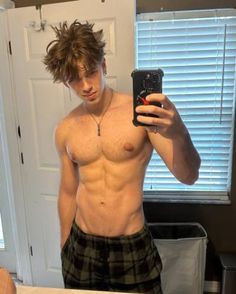 a shirtless man taking a selfie in front of a mirror with his cell phone