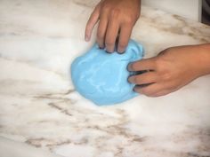 a person holding a blue object on top of a white marble countertop next to a sink