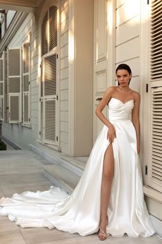 a woman in a white dress leaning against a wall