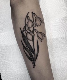 a black and white flower tattoo on the left arm, with flowers in it's center