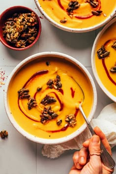 three bowls filled with soup and topped with nuts