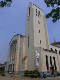 a tall white building with a clock on it's side and a statue in front